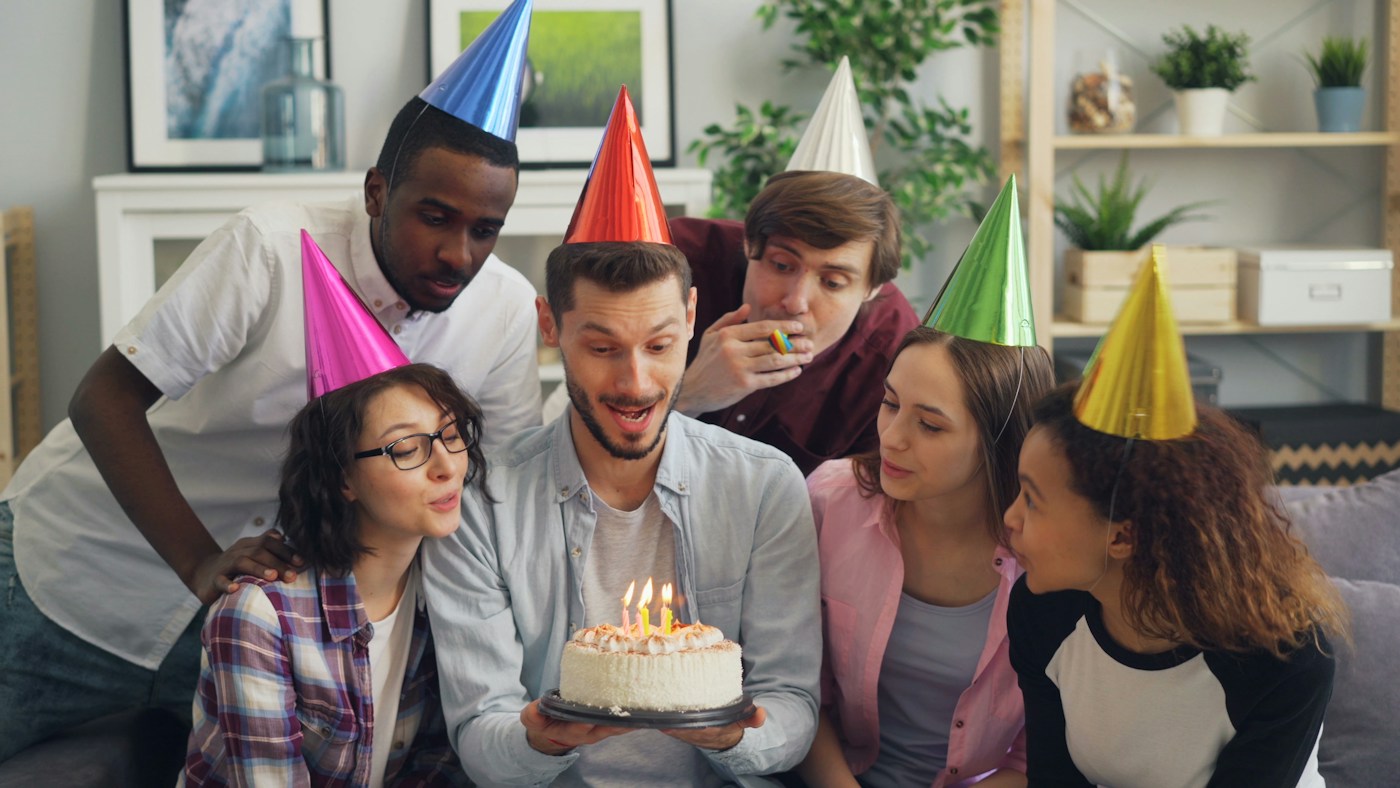 Friends in party hats blowing out birthday candles